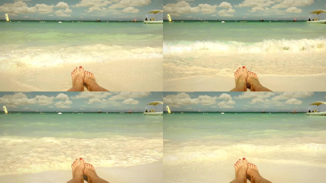 在热带海滩上，一个有着红色指甲的女人的脚。