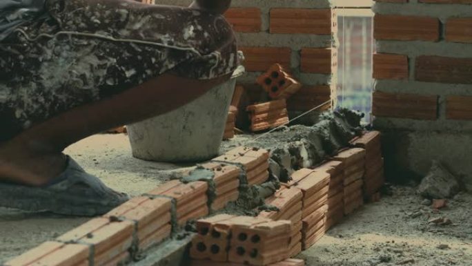 4k镜头特写手工专业建筑工人在新工业场地、建筑行业和砖石概念中砌砖的场景