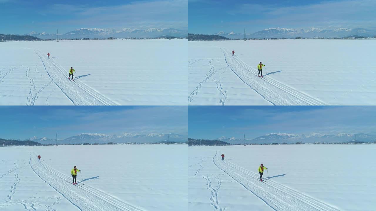 空中: 两名女性游客在阳光明媚的日子里滑雪越野赛。