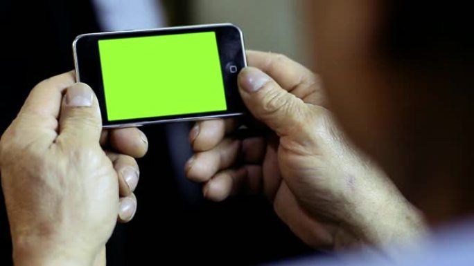 男子拿着一部绿屏智能手机。放大。