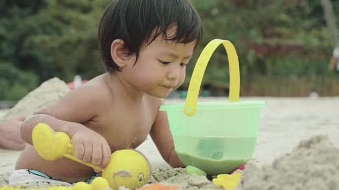 亚洲男婴在海滩上玩沙堡