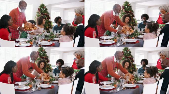 祖父在多代混血家庭圣诞节庆祝活动中将烤火鸡带到餐桌上
