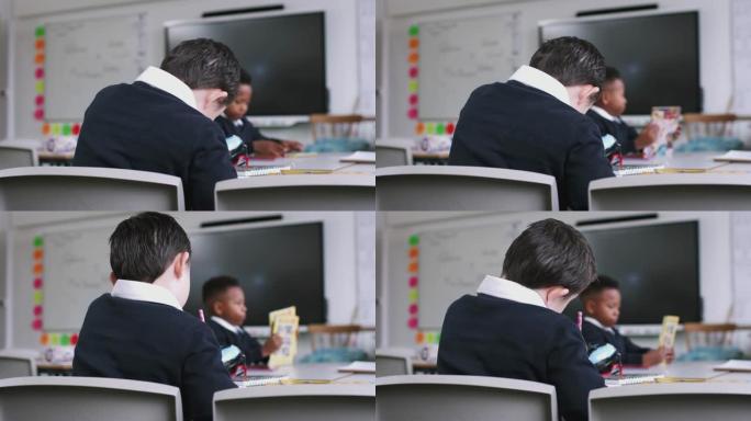 患有唐氏综合症的男孩坐在小学课桌上的背景图，特写