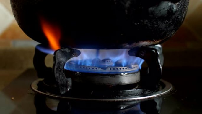 燃气灶上的旧锅蓝色火焰火苗