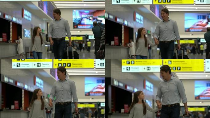 慈爱的爸爸和女儿在机场牵着手一起散步，同时各自拉着行李