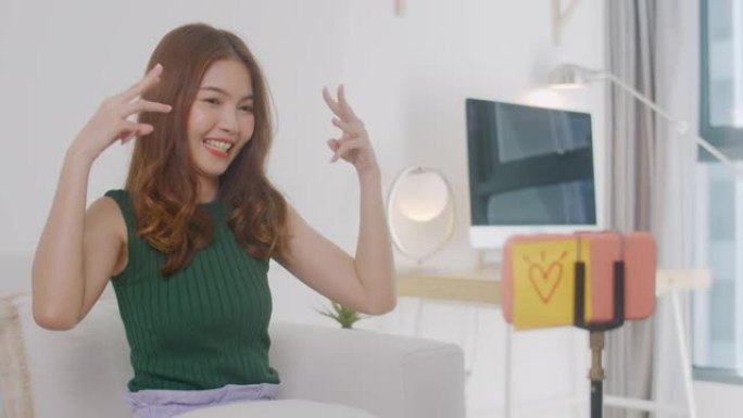 美丽的亚洲女人通过智能手机应用程序跳舞，在线社交概念，在日冕病毒流行期间在家休闲活动