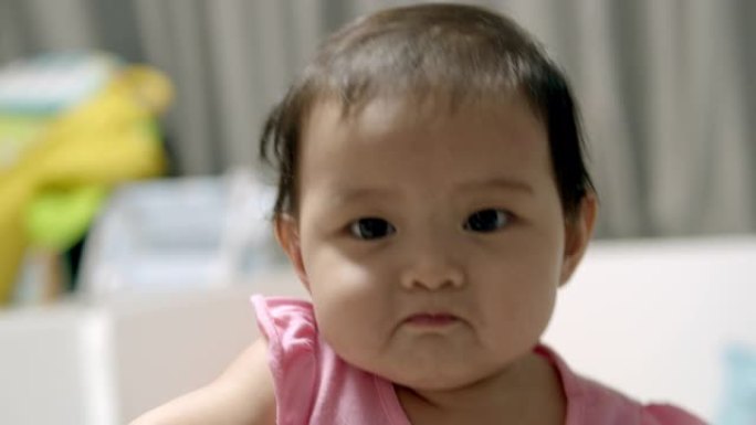 穿着粉色连衣裙的亚洲8个月女婴喜欢在家玩耍。