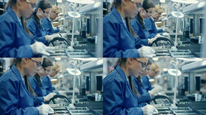 穿着蓝色工作服和防护眼镜的女电子工厂工人，用镊子组装智能手机的印刷电路板。背景员工更多的高科技工厂。