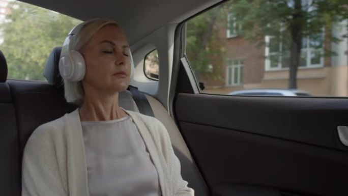 戴着耳机的女人在开车时在电话上听音乐