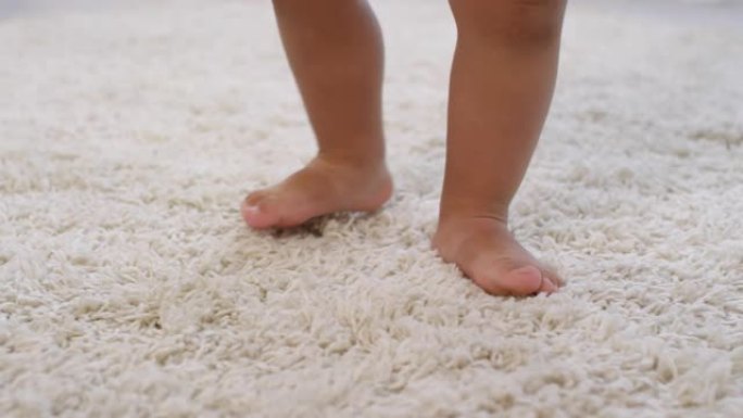 无法识别的蹒跚学步的腿在地毯上行走和掉落玩具