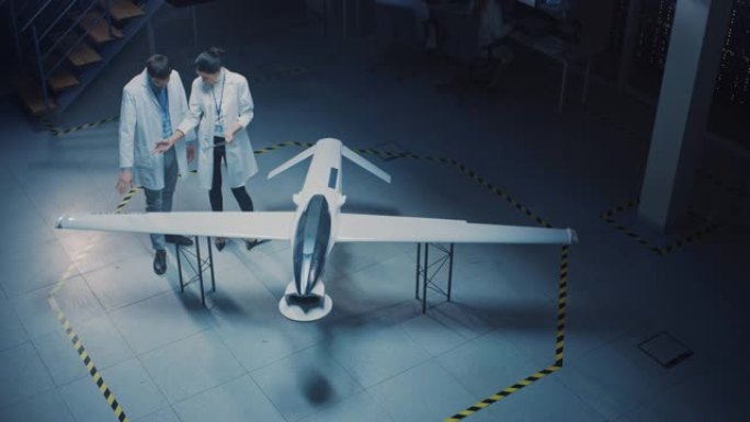 两名航空航天工程师在无人飞行器/无人机原型上工作。穿着白大褂说话的航空科学家，使用平板电脑。带有监视