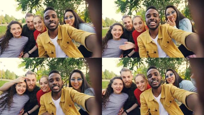 快乐的朋友正在网上视频通话，看着相机，说笑，而非洲裔美国人在公园野餐时拿着相机的设备。