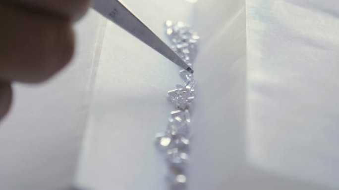 一个金匠的特写镜头，看着并展示了一颗珍贵的钻石。