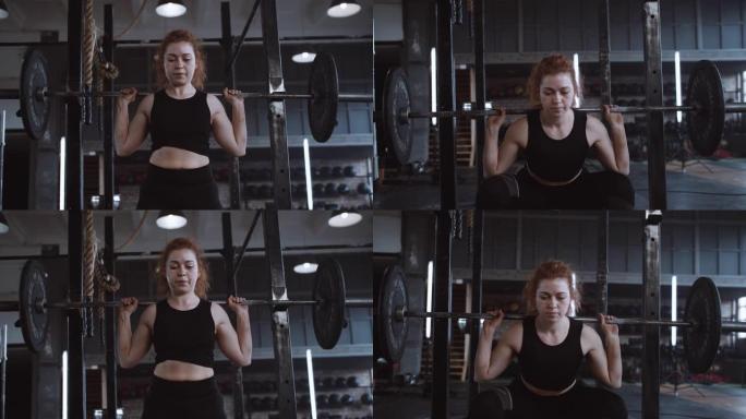 年轻美丽的高加索红头发运动女子举起沉重的杠铃站在大型专业健身房慢动作