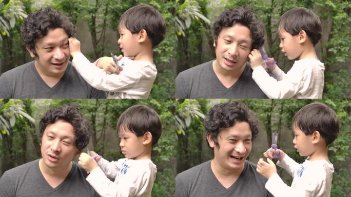一对父子在家里一起玩，儿子拿着剪刀在家里当理发师或美发师给父亲理发。居家隔离冠状病毒大流行预防，社会