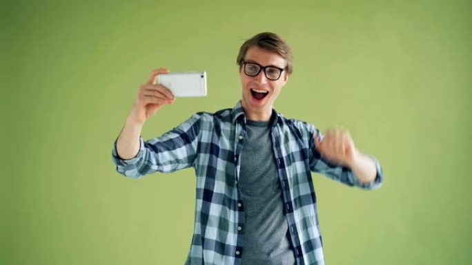 快乐的家伙用智能手机相机自拍的肖像玩得开心