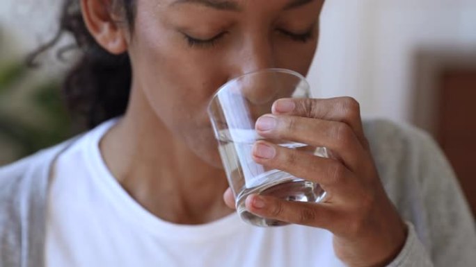 口渴脱水的非洲妇女拿着玻璃喝水，特写镜头