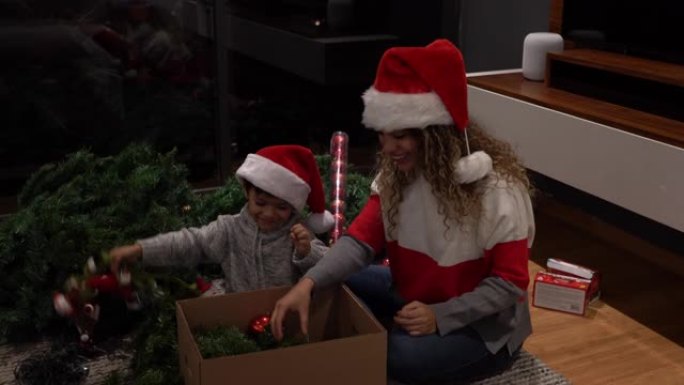 美丽的母亲和儿子从盒子里拿出圣诞装饰品，当他们找到星星时，他们都非常兴奋