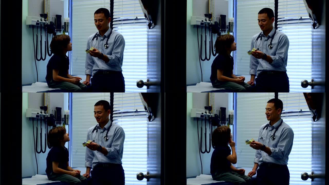 年轻的亚洲男医生在诊所4k向白人男孩患者展示耳朵模型的侧视图