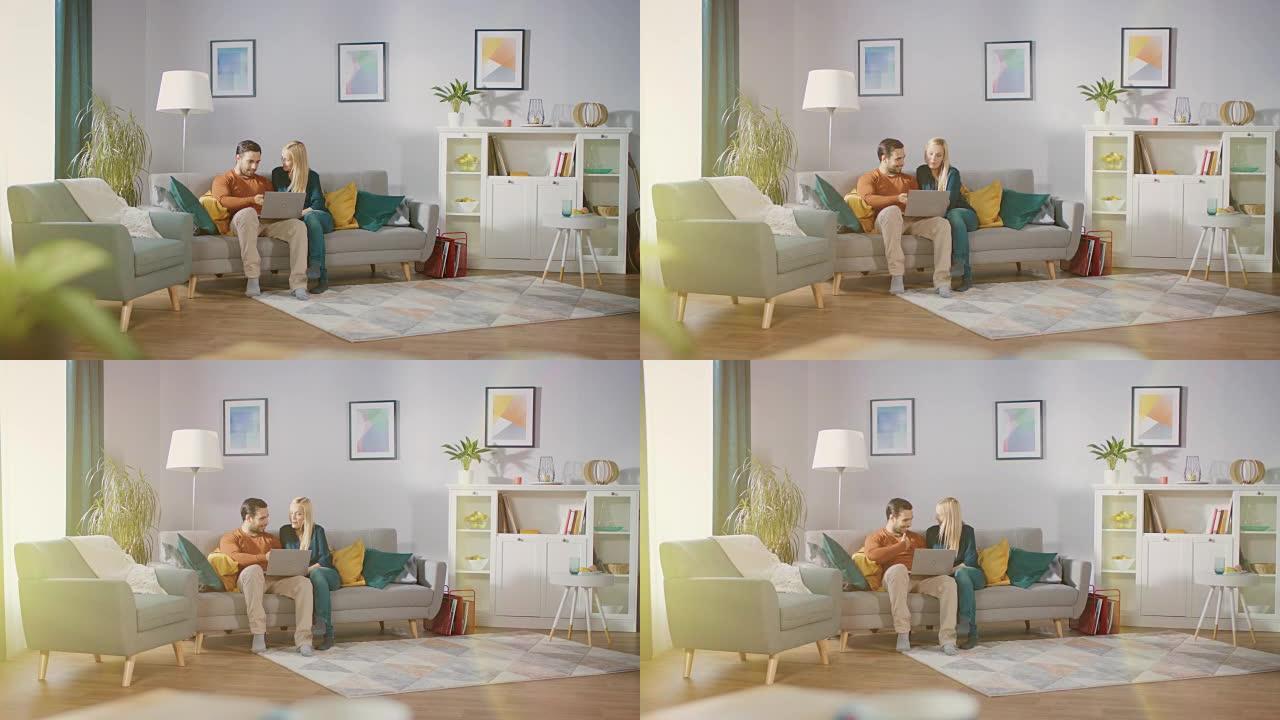 幸福可爱的夫妇坐在家里的沙发上，男朋友膝盖上拿着笔记本电脑，浏览互联网，使用流媒体服务进行电子购物。