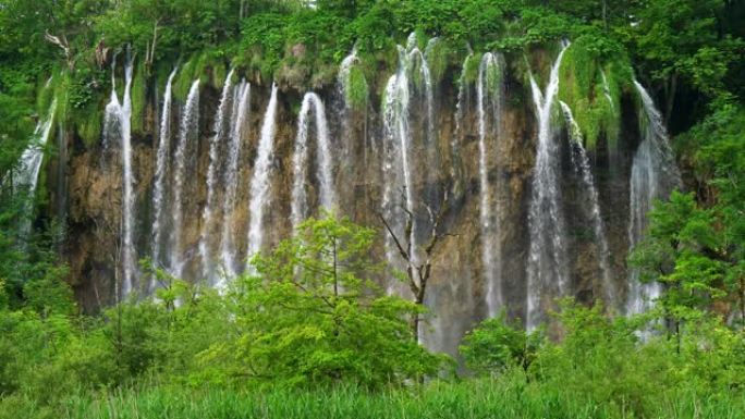克罗地亚十六湖国家公园。瀑布中的水从岩石流入湖泊。都被丰富的绿色包围着。UHD