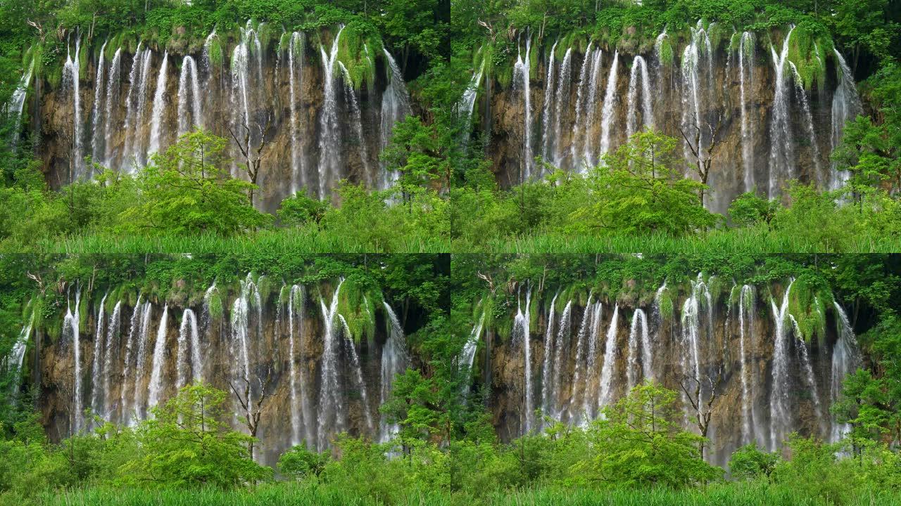 克罗地亚十六湖国家公园。瀑布中的水从岩石流入湖泊。都被丰富的绿色包围着。UHD