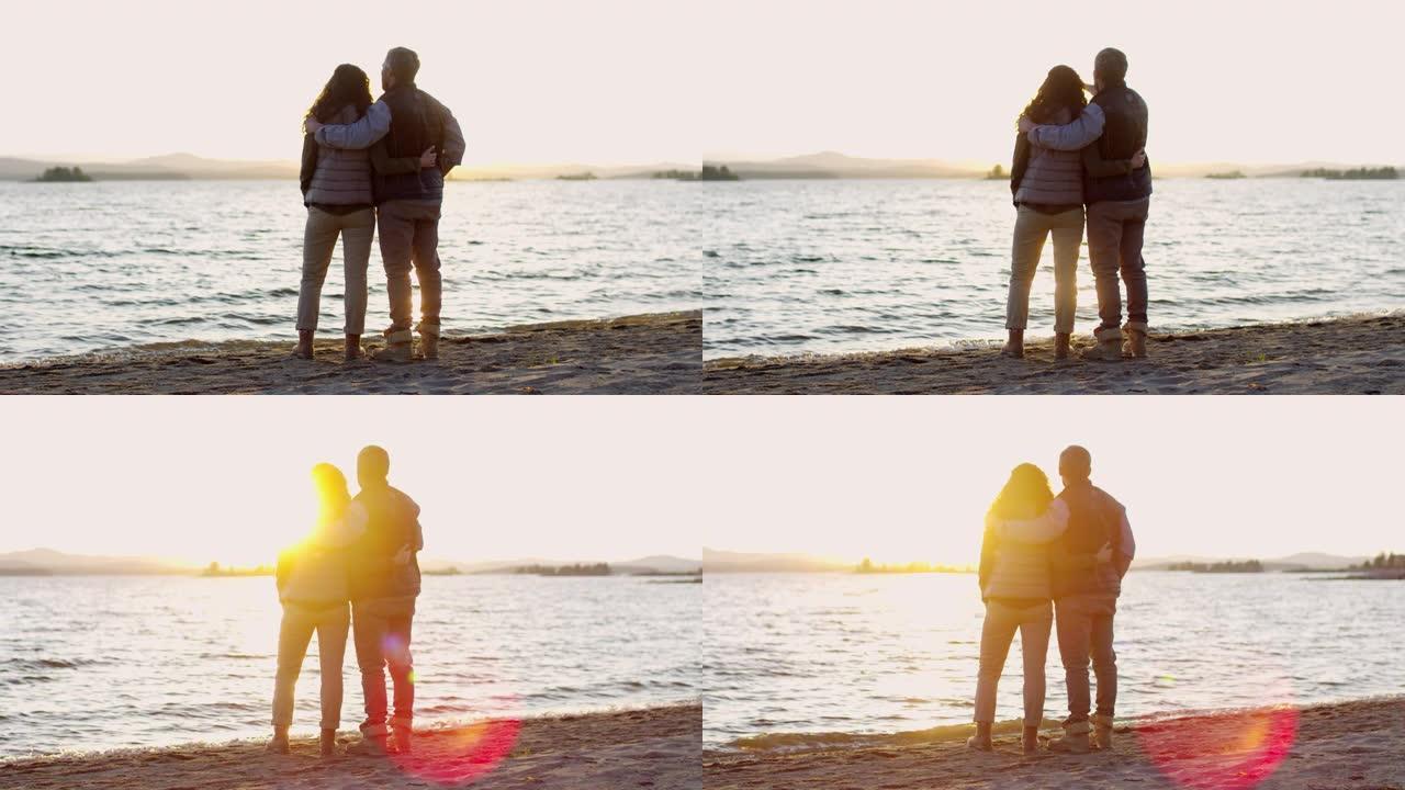 浪漫的情侣从湖岸拥抱和观看日落