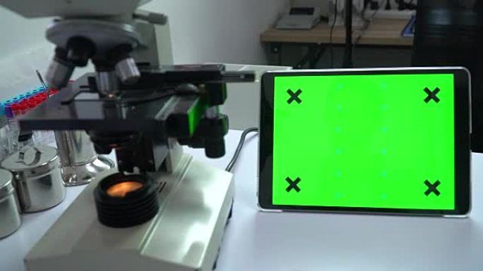 女研究科学家坐在实验室的工作场所，使用绿色模拟屏幕个人计算机
