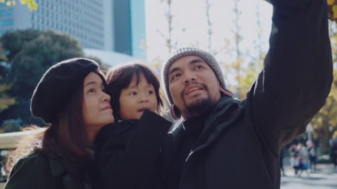 家庭在东京与秋叶在手机上摆姿势自拍。