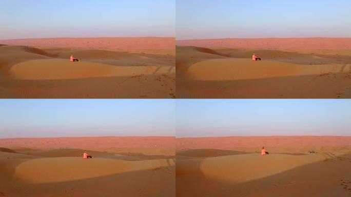 坐在沙漠中的沙丘上的空中游客