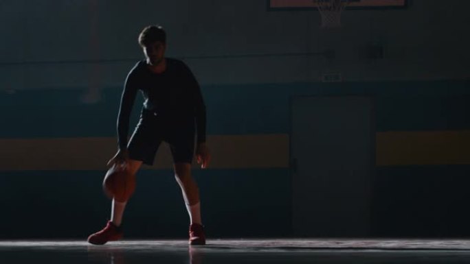 一名年轻职业男球员的电影慢动作镜头正在健身房练习篮球运动