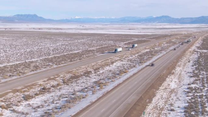 无人机: 卡车沿着一条高速公路运送货物，穿越犹他州的雪域。
