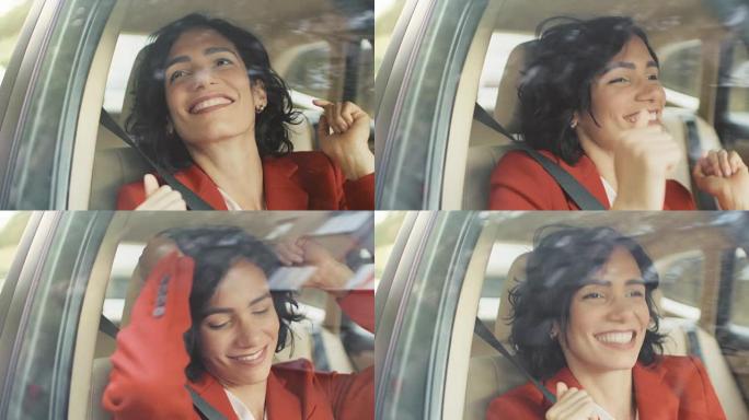美丽的幸福女人坐在汽车的乘客座位上，她很开心，跳舞。大城市的景色反映在窗口中。摄像机安装在移动汽车外
