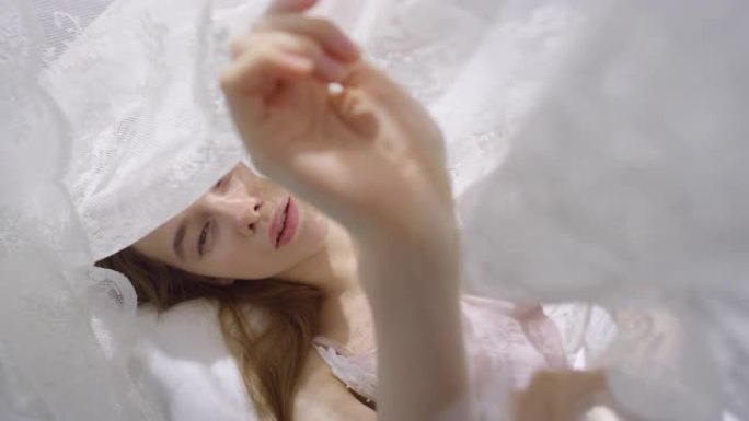 性感的女人躺在带盖的床上