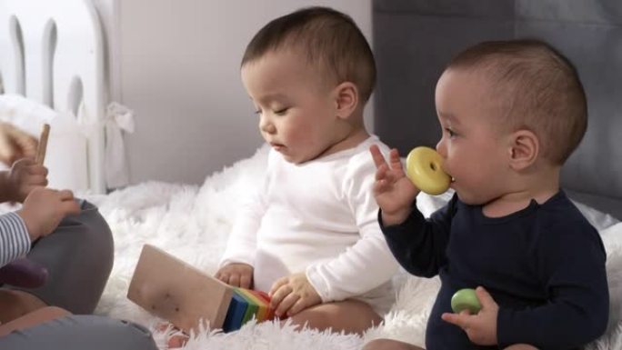 亚洲三胞胎婴儿坐在卧室里玩玩具