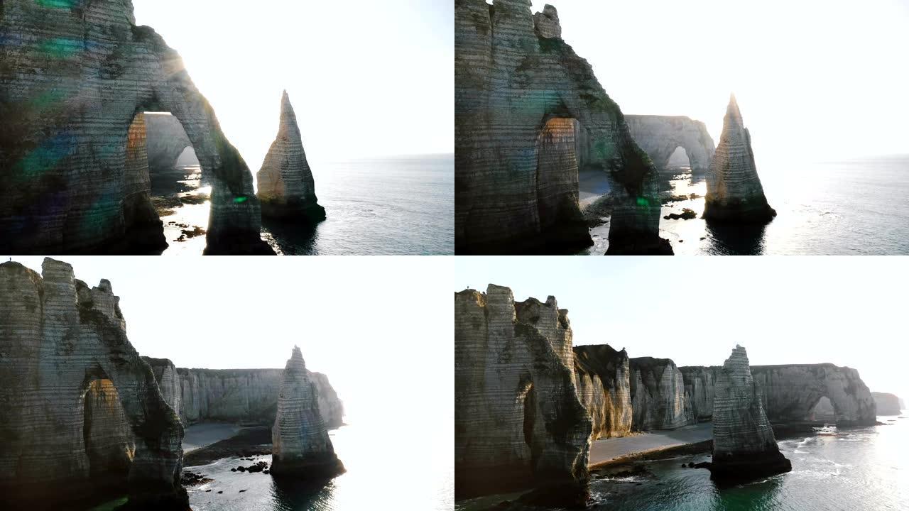 美丽的背光无人机全景，诺曼底著名的白海悬崖上巨大的自然侵蚀岩石拱门和支柱。