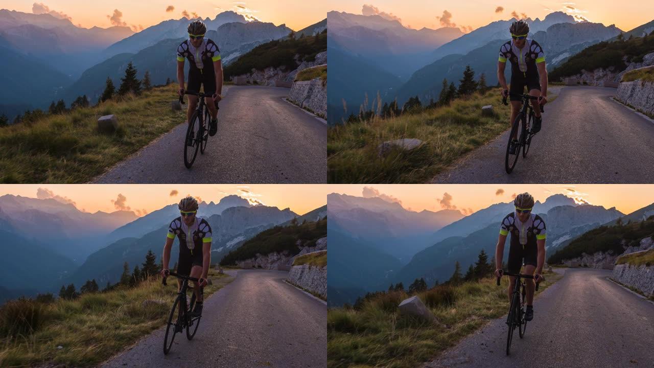 在一个温暖的夏日夜晚，在山口上的男性公路自行车手