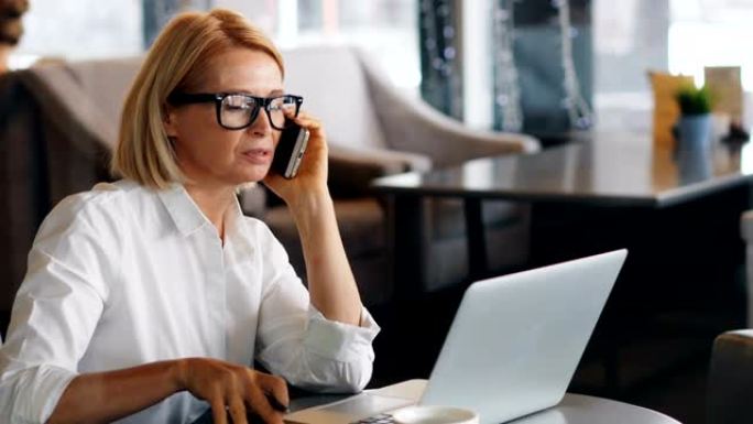 美丽的商务女士在手机上聊天检查笔记本电脑和笔记本电脑