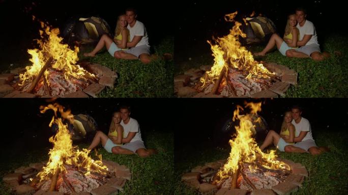 慢动作: 无忧无虑的旅游夫妇在野外露营，在火炉旁拥抱。