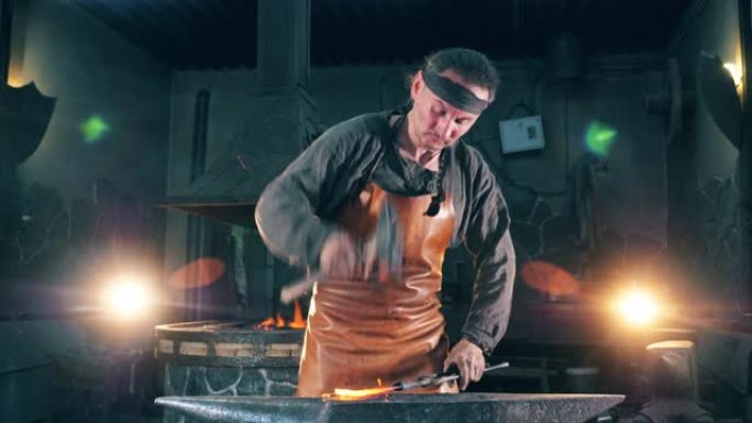 专业铁匠在铁砧上用锤子塑造刀。
