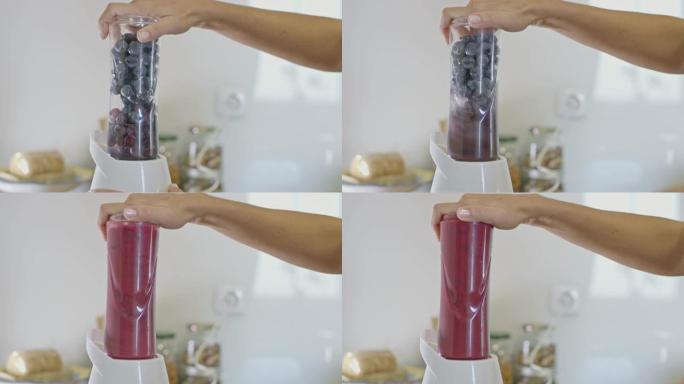 CU妇女在榨汁机中榨汁蓝莓和葡萄