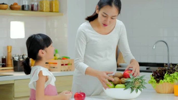 怀孕的母亲和女儿在厨房做沙拉。怀孕/出生