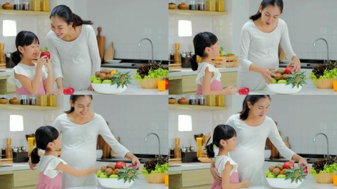 怀孕的母亲和女儿在厨房做沙拉。怀孕/出生