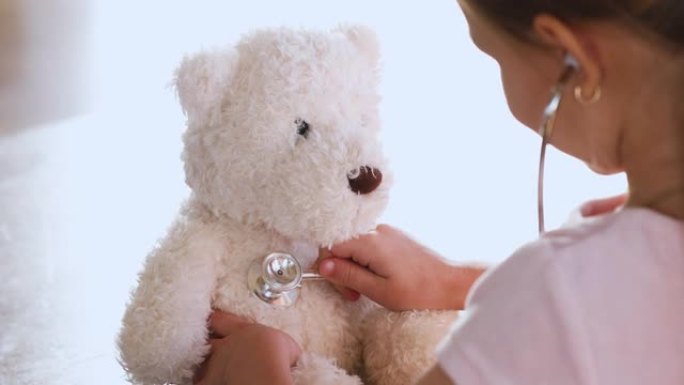 扮演医生的女孩拿着听诊器听泰迪熊，特写