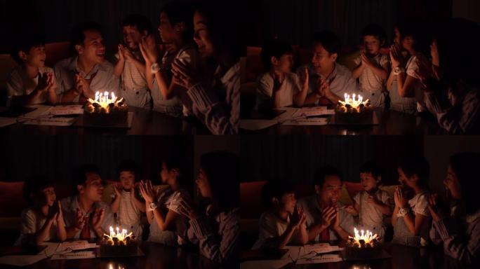 庆祝和家庭概念-快乐的父亲在家里的晚宴上在生日蛋糕上吹蜡烛。