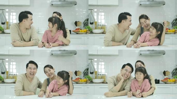 母亲，父亲和女儿的亚洲幸福家庭坐在厨房里，在镜头前微笑着。肖像照。室内