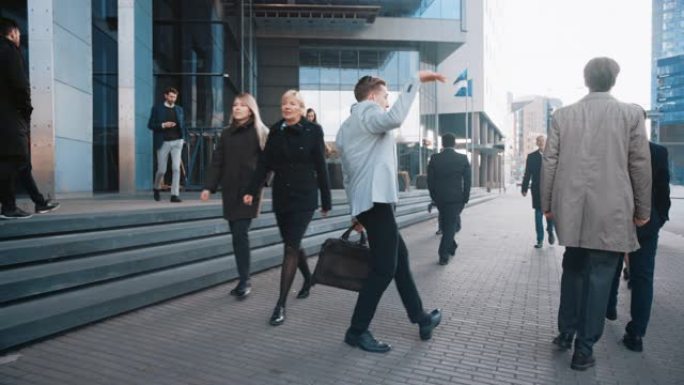 穿着灰色西装外套的开朗年轻商人正在城市街道上积极跳舞。办公室经理穿过繁忙的办公室人群上下班。他拿着一