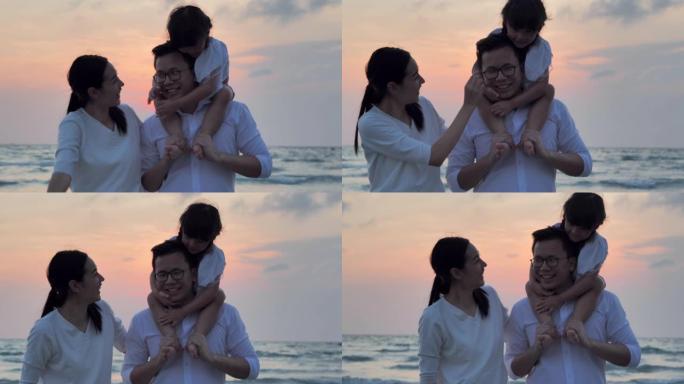 剪影快乐的父亲，母亲，女儿背负式骑行，在沙滩上沿着日落海上冲浪的边缘玩耍。父亲背着小女孩。家庭假期快