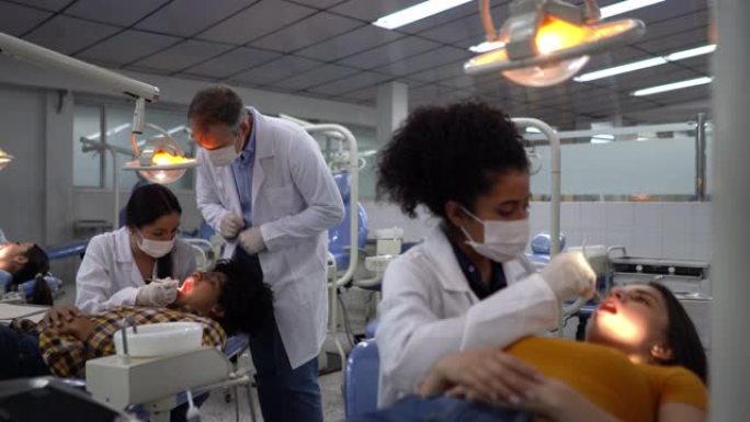 一组学生在牙科课上检查患者，而男老师则监督
