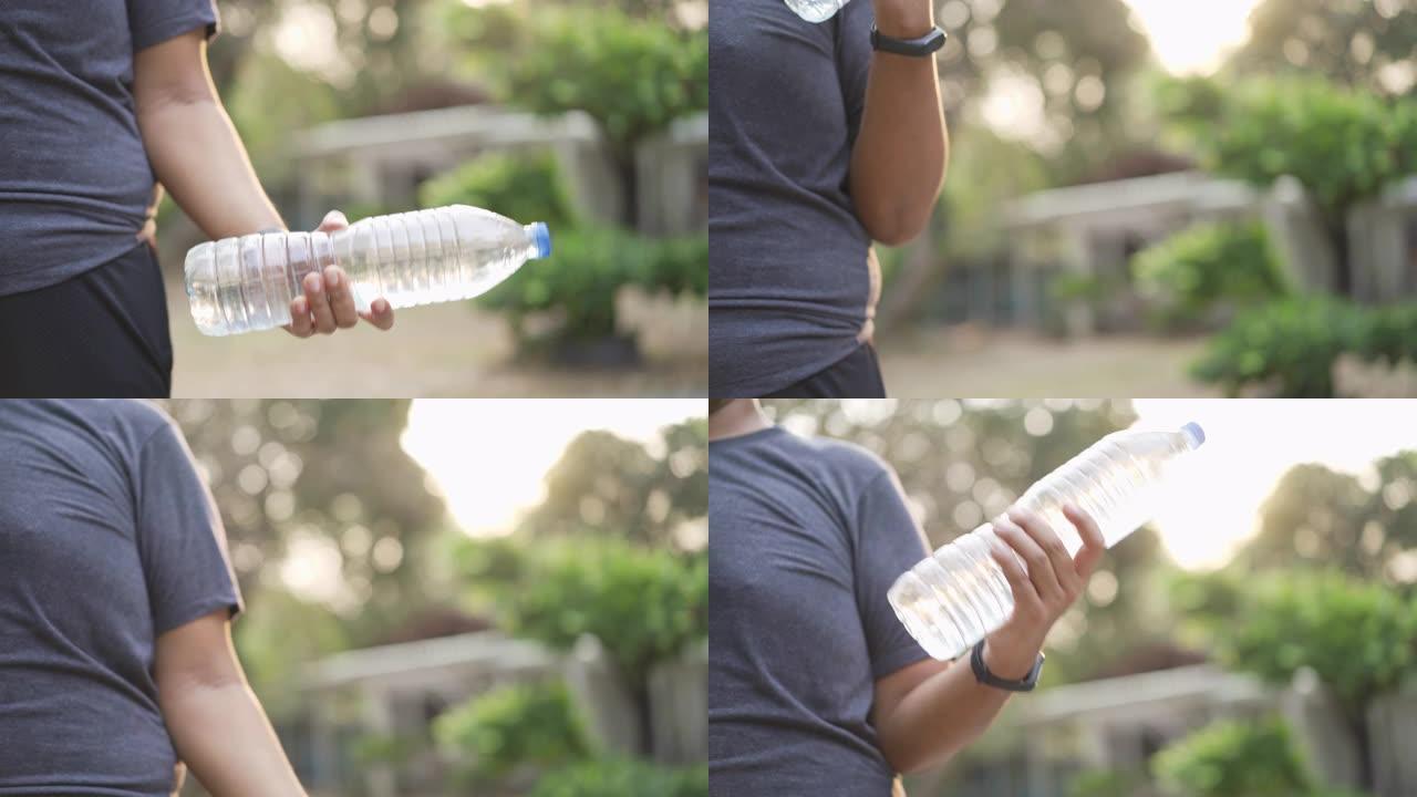 超重的亚洲男子使用水瓶代替健身房在家锻炼检疫新型冠状病毒肺炎电晕病毒情况